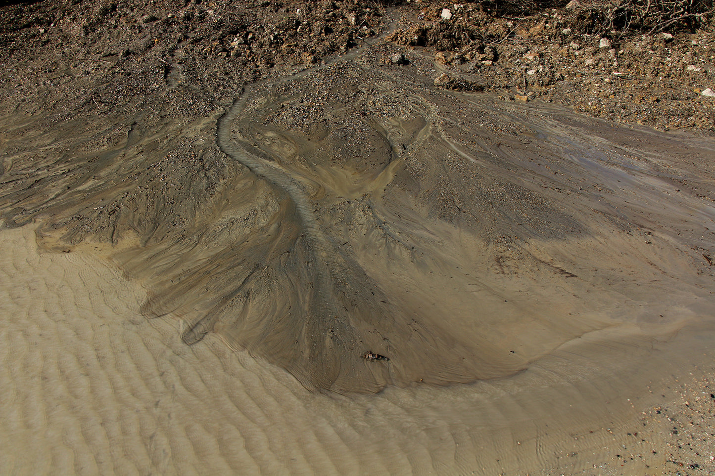 Alluvial fan stratigraphy image. Water flows over tannish-brown sand and rock.