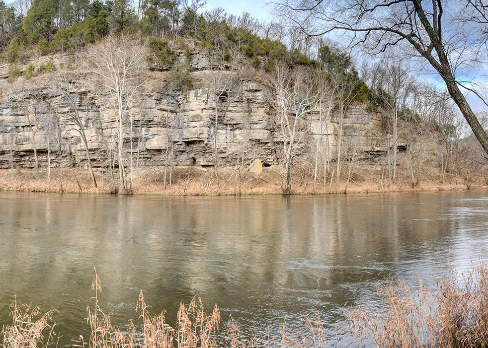 Panoramic view of a river with a rocky cliff in the background