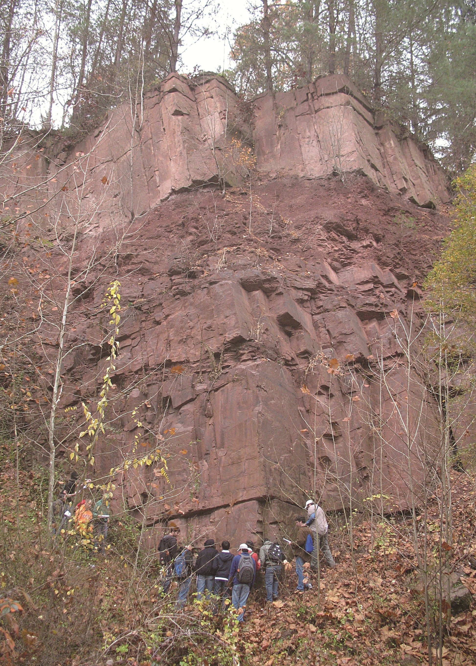 Group of people exploring a rocky cliff face in a forested area, New Jersey