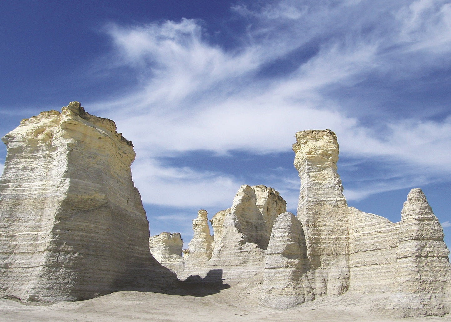 White sandstone formations against a blue sky with scattered clouds. Monument Rocks, Kansas