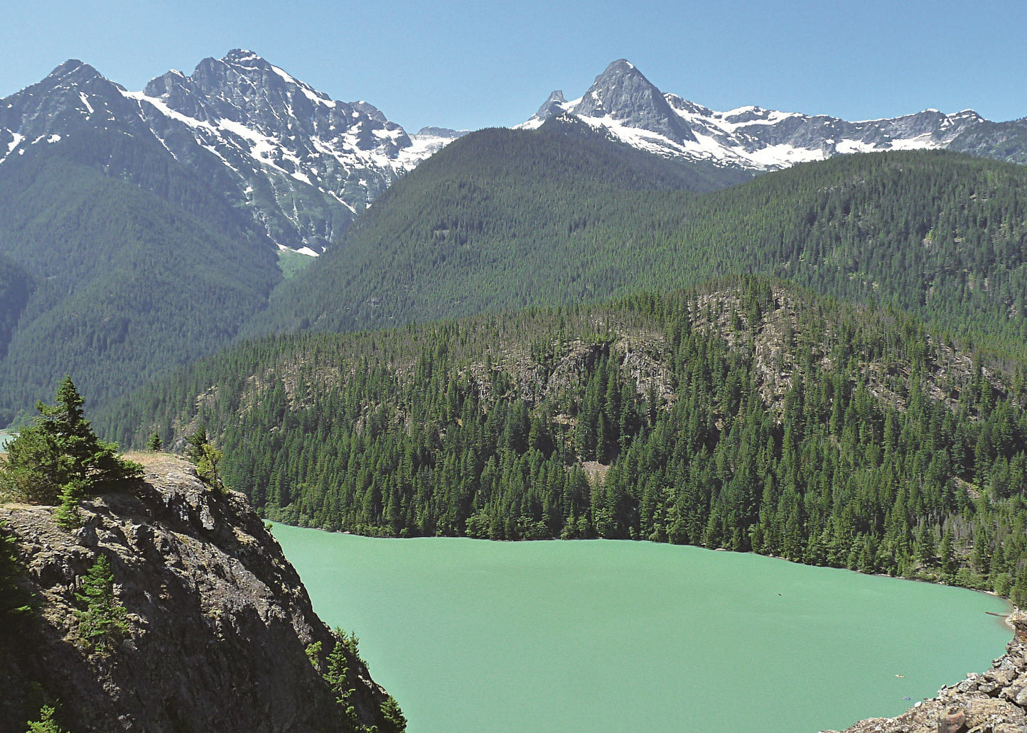 Lake surrounded by forested mountains with snow-capped Colonial Peak and Pyramid Peak, Washington 