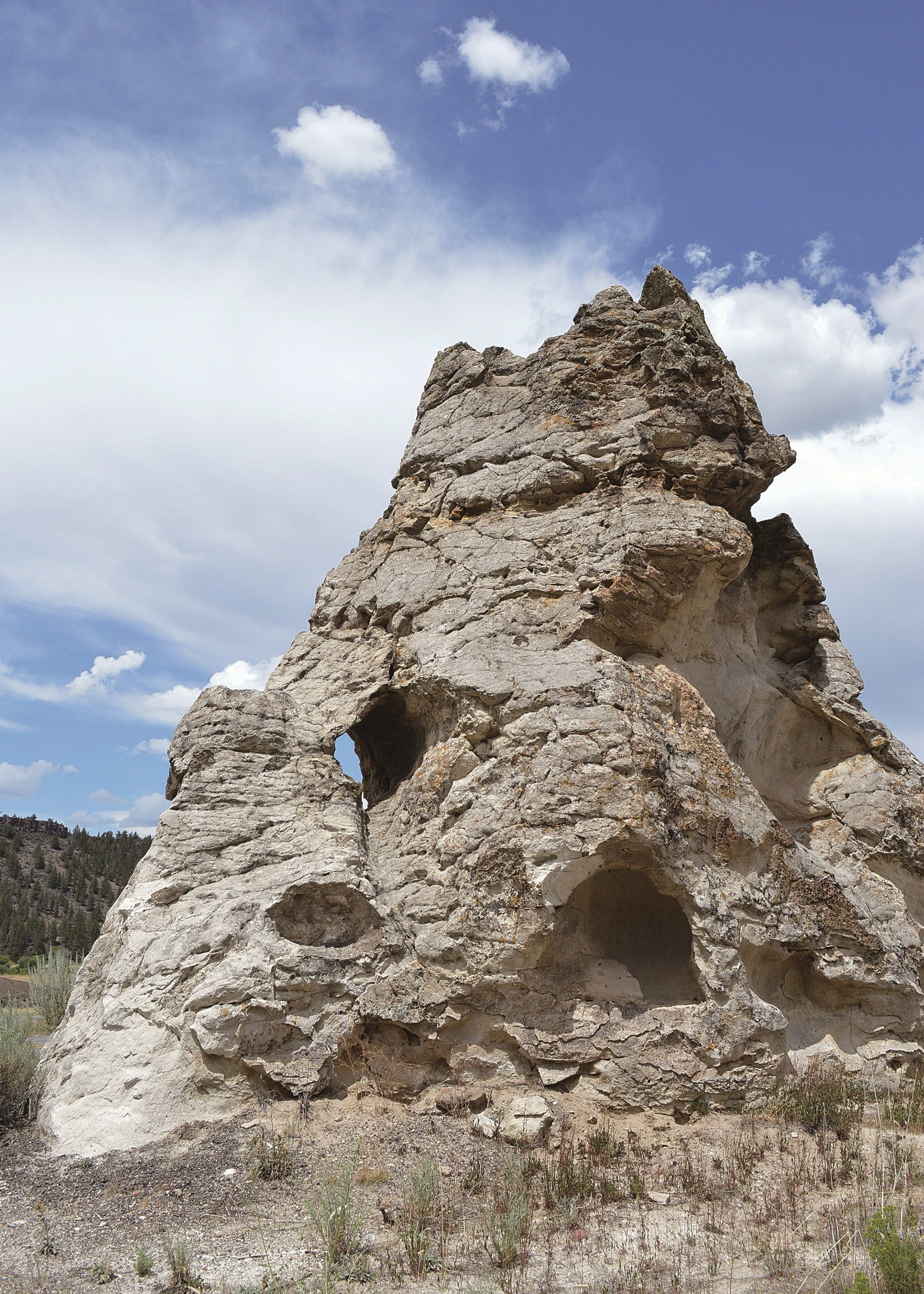 Rock formation with natural erosion in a desert landscape under a blue sky with clouds.