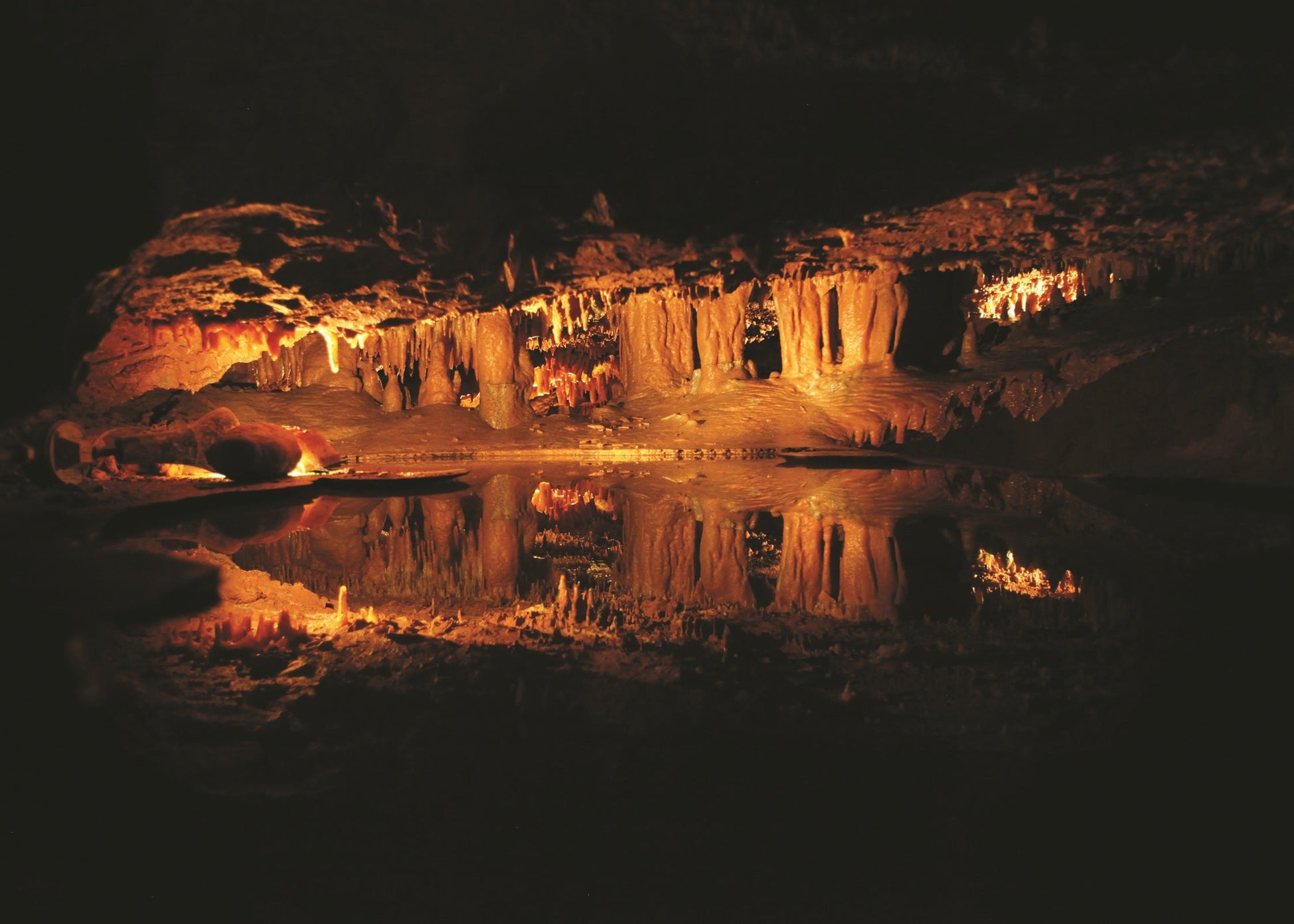 Cave with illuminated rock formations reflected in water. Dixie Caverns, Virginia