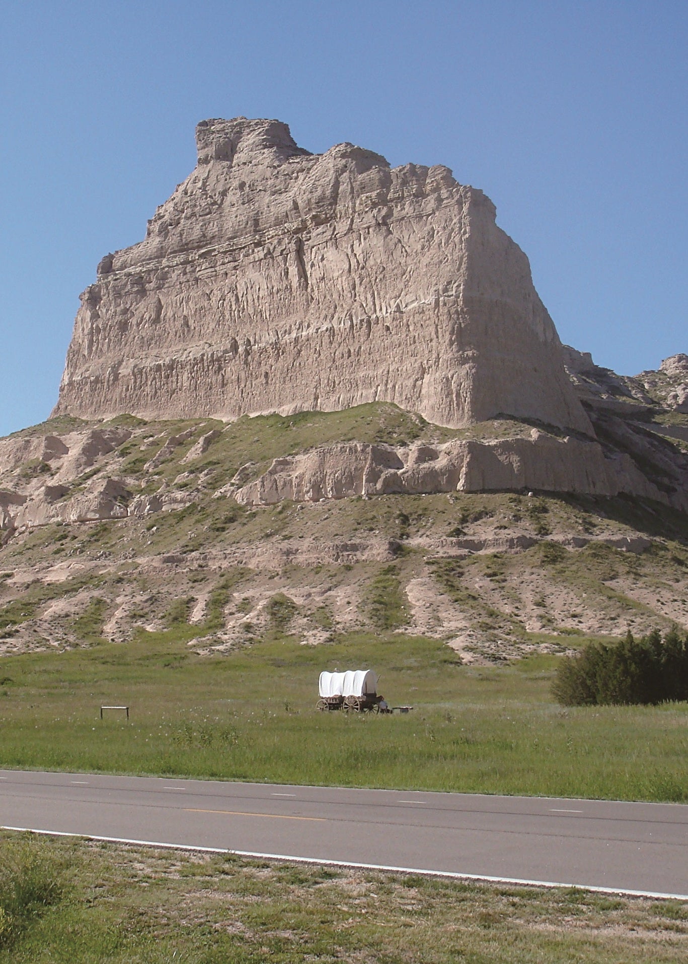Large rock formation in a grassy landscape with a clear blue sky, Scottsbluff Nebraska