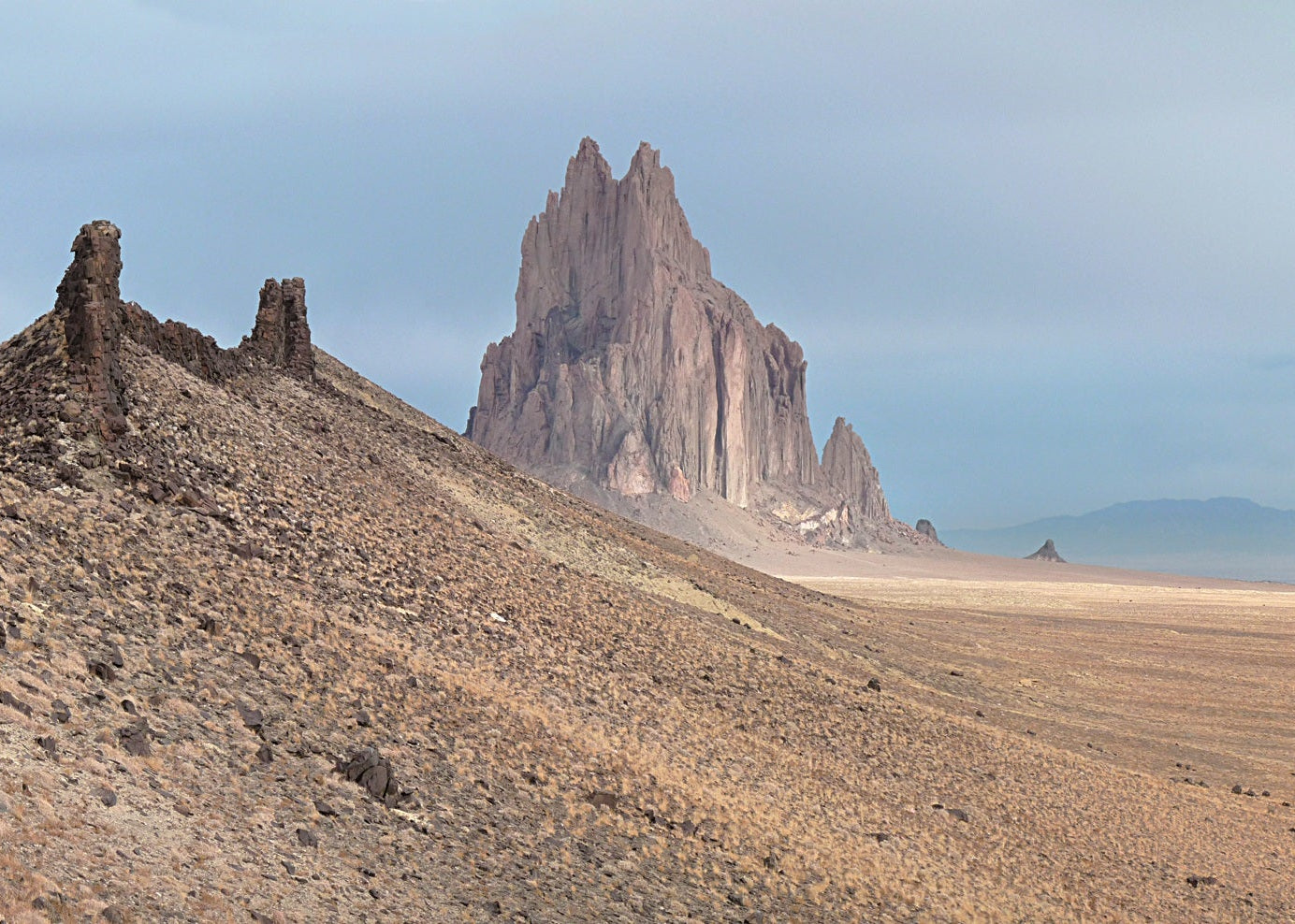 Desert landscape with prominent rock formations under a clear sky, Ship Rock New Mexico