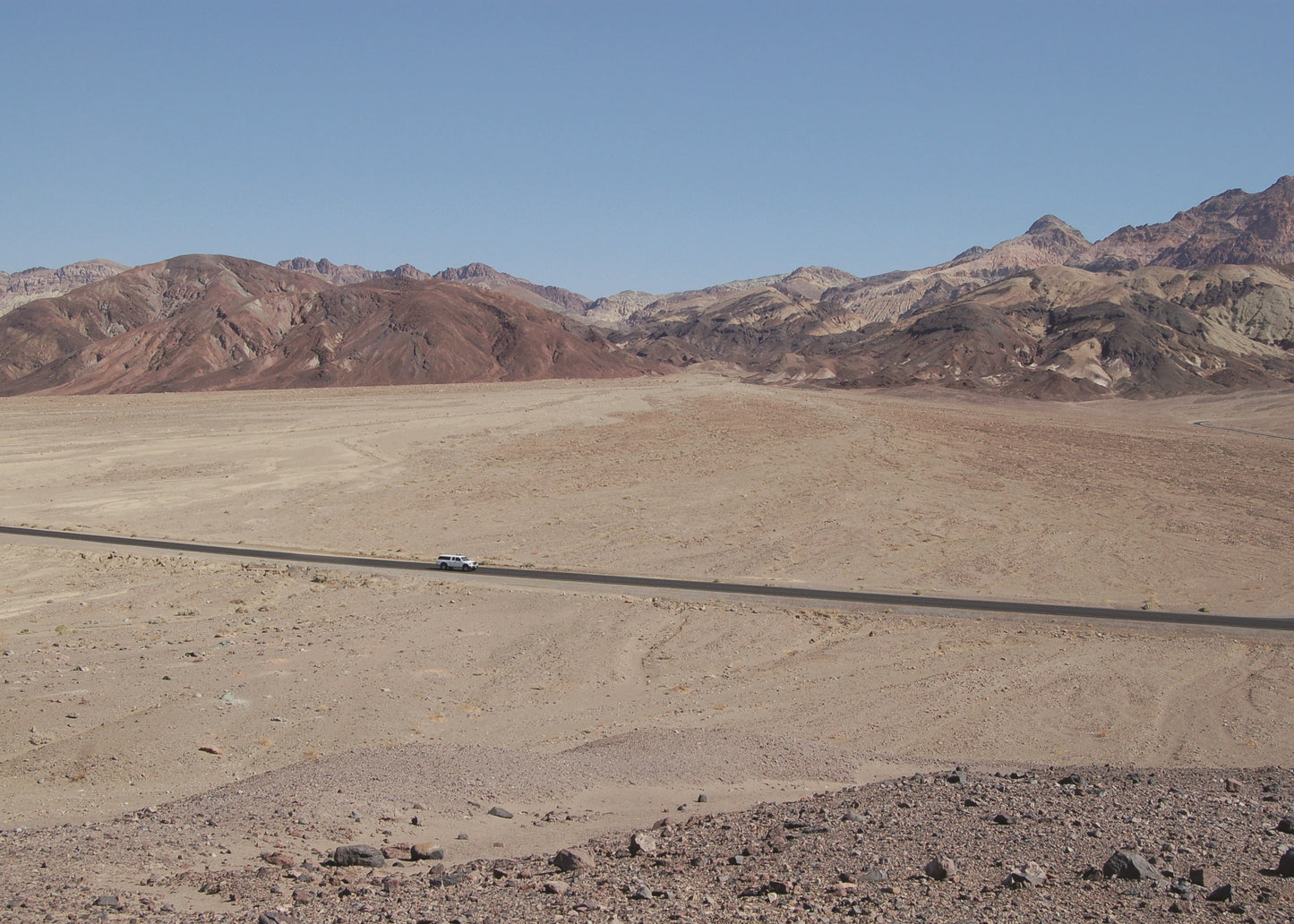 Desert landscape with mountains in the background and a road stretching into the distance.
