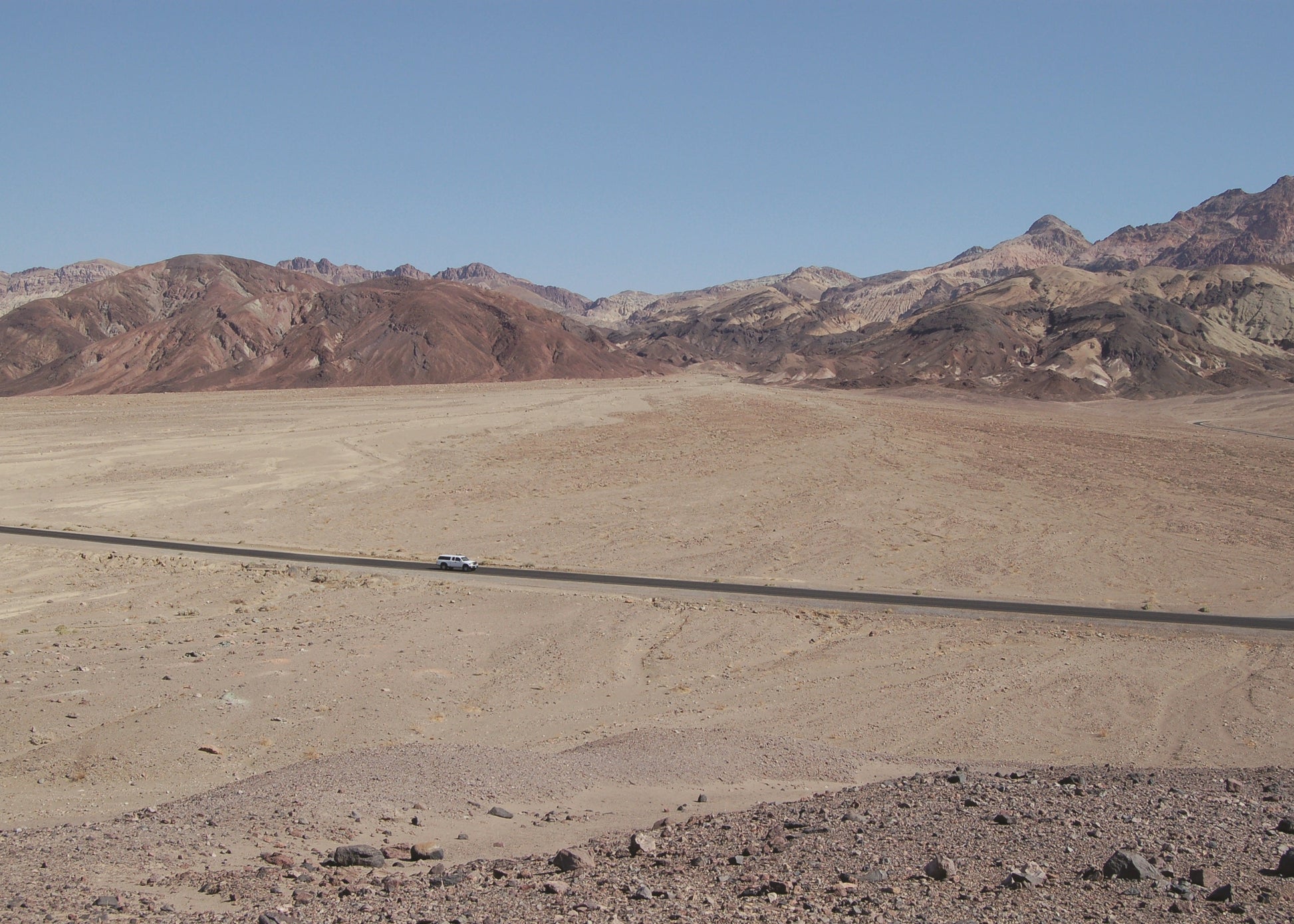 Desert landscape with mountains in the background and a road stretching into the distance.