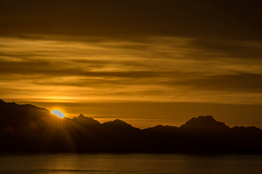 Sun sets over mountainous land bordered by a body of water. Isla del Carmen, México image.