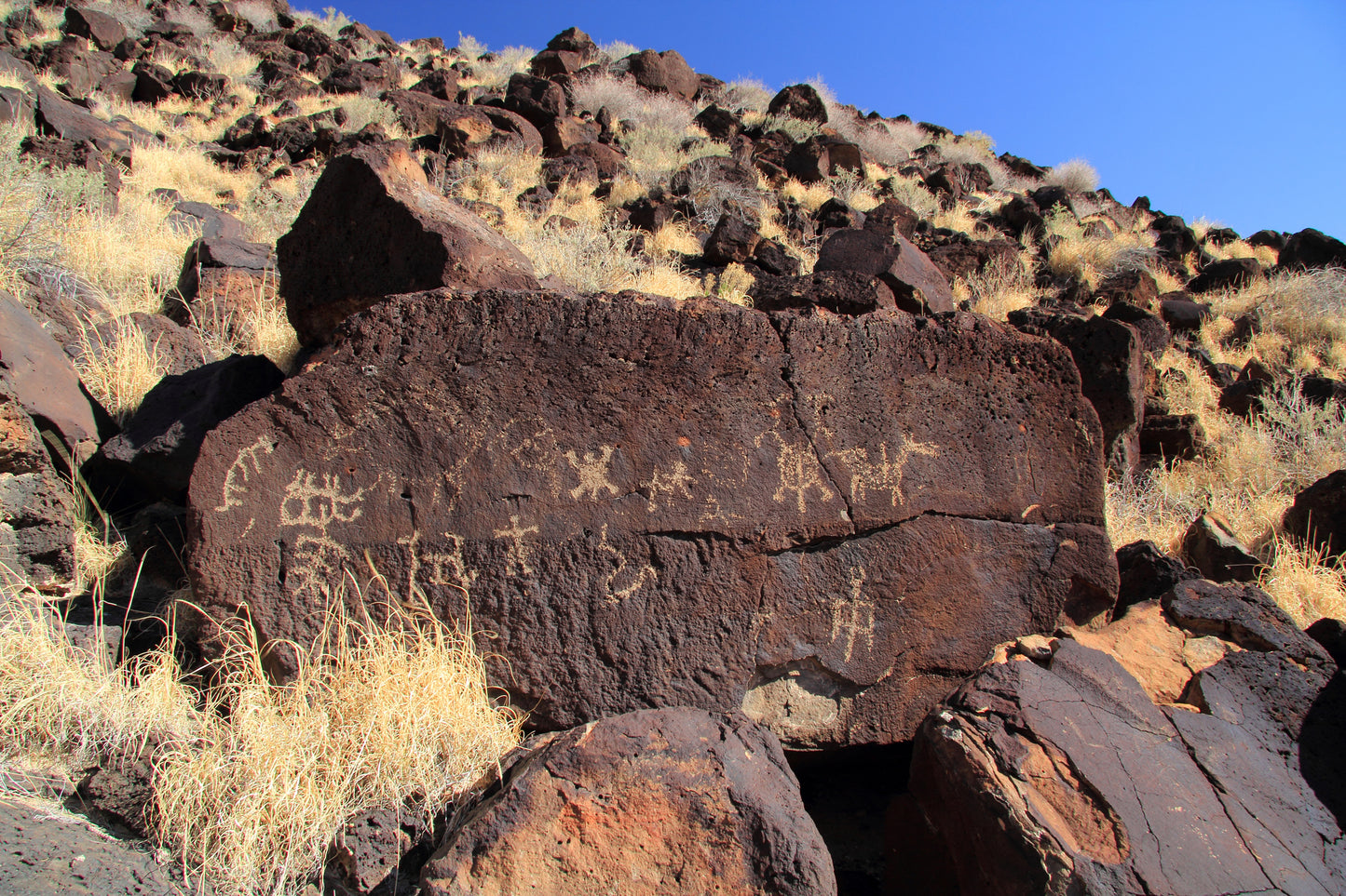 Indigenous Geology in NM image. Rock with petroglyphs in a desert landscape.