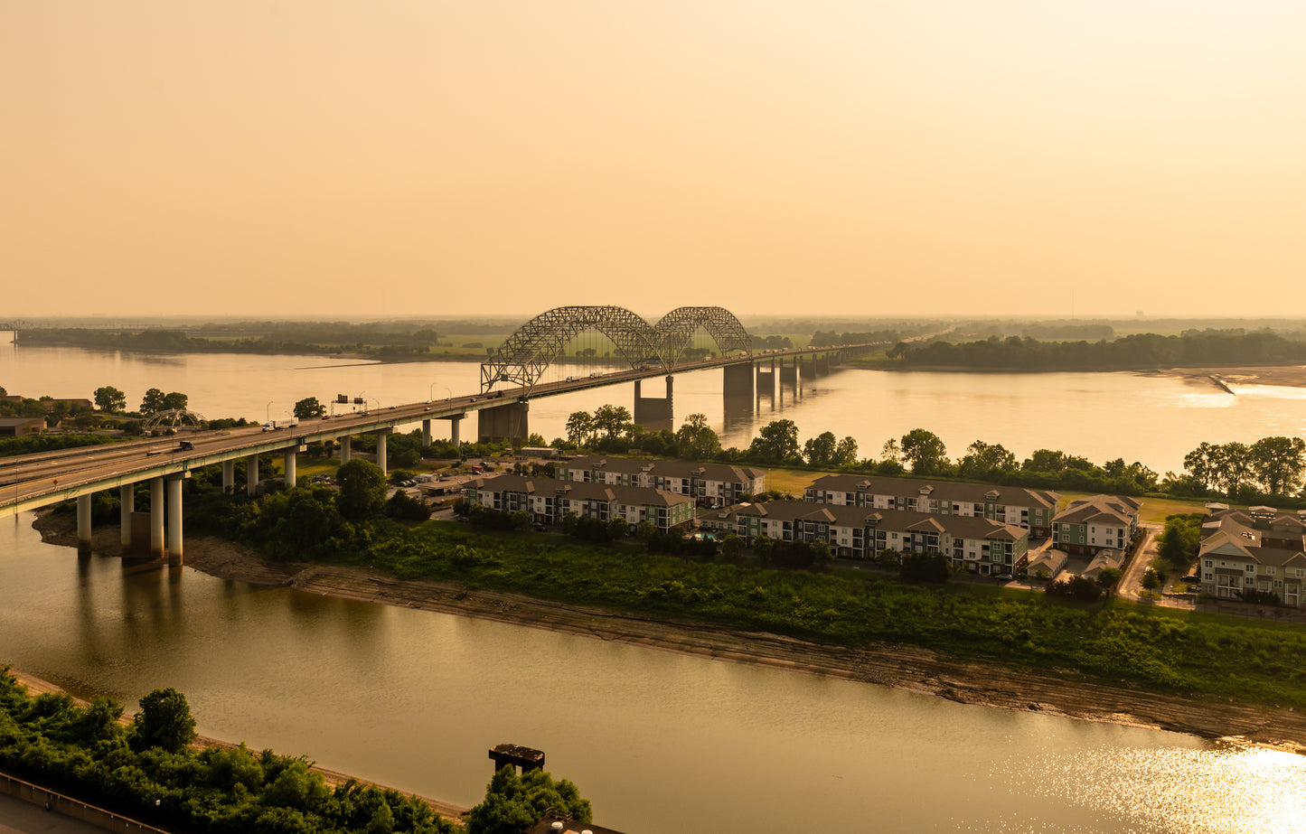 A large bridge goes from the foreground to the background and over waterways. Between the waterways is a green swath of land with houses. Toxic Tour image.