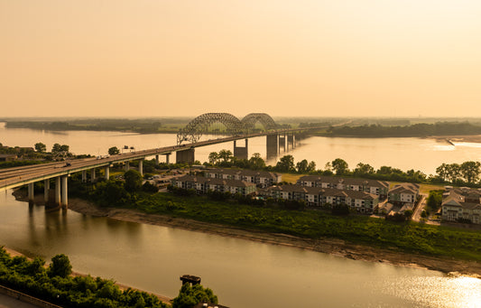A large bridge goes from the foreground to the background and over waterways. Between the waterways is a green swath of land with houses. Toxic Tour image.