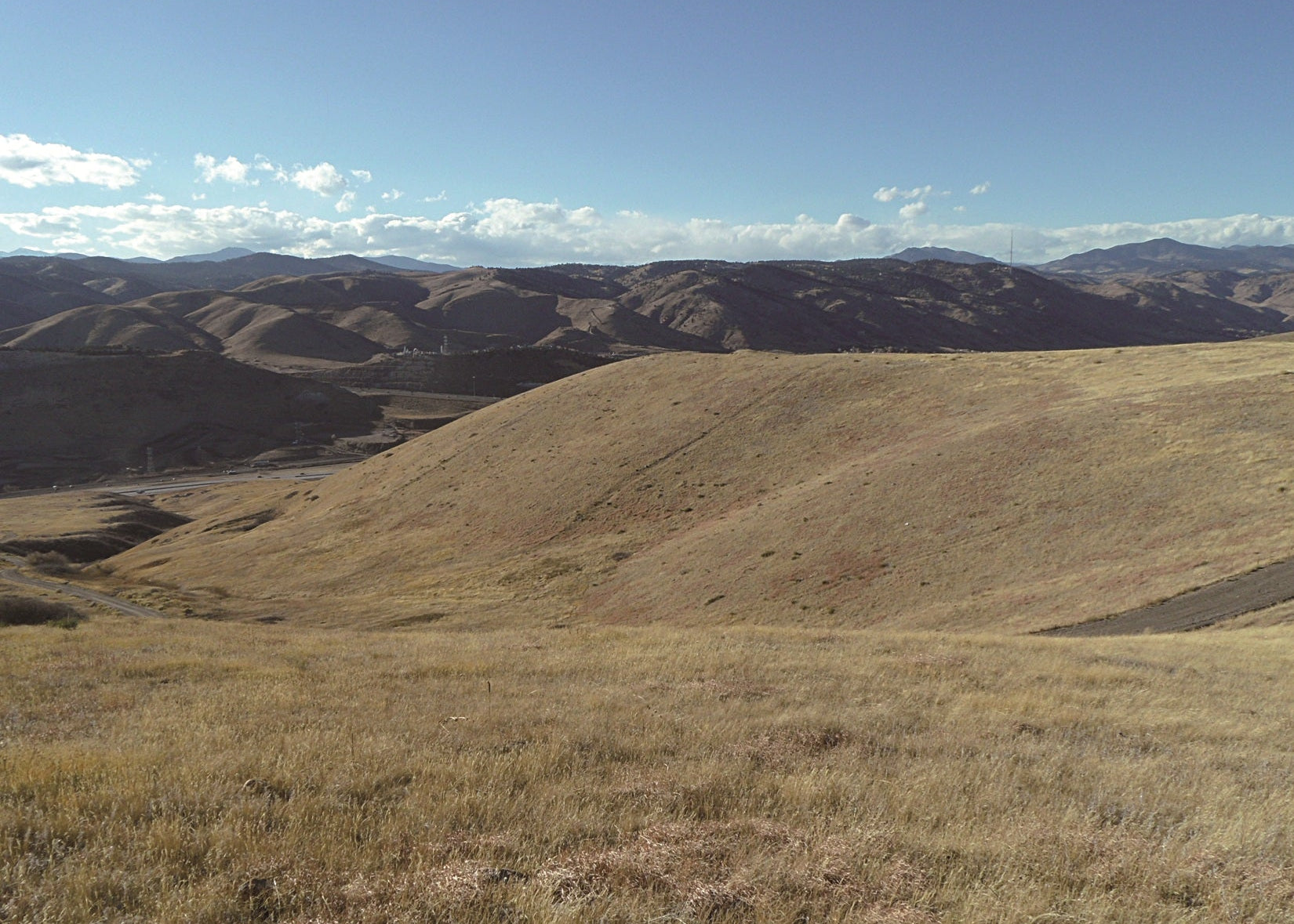 Scenic view of rolling hills with mountains in the distance under a blue sky. Green Mountain, Colorado 