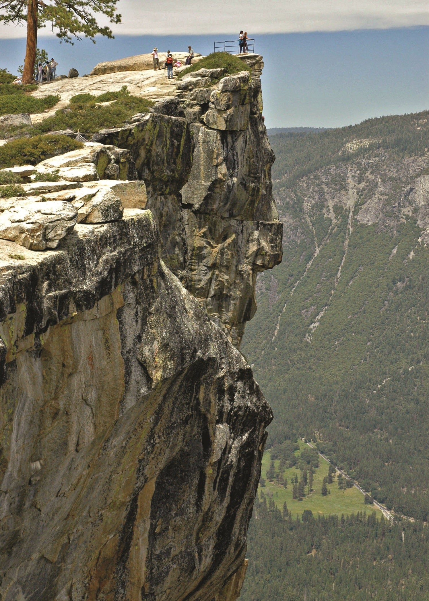 Scenic view of a rocky cliff with a valley below and people at the top, Yosemite National Park