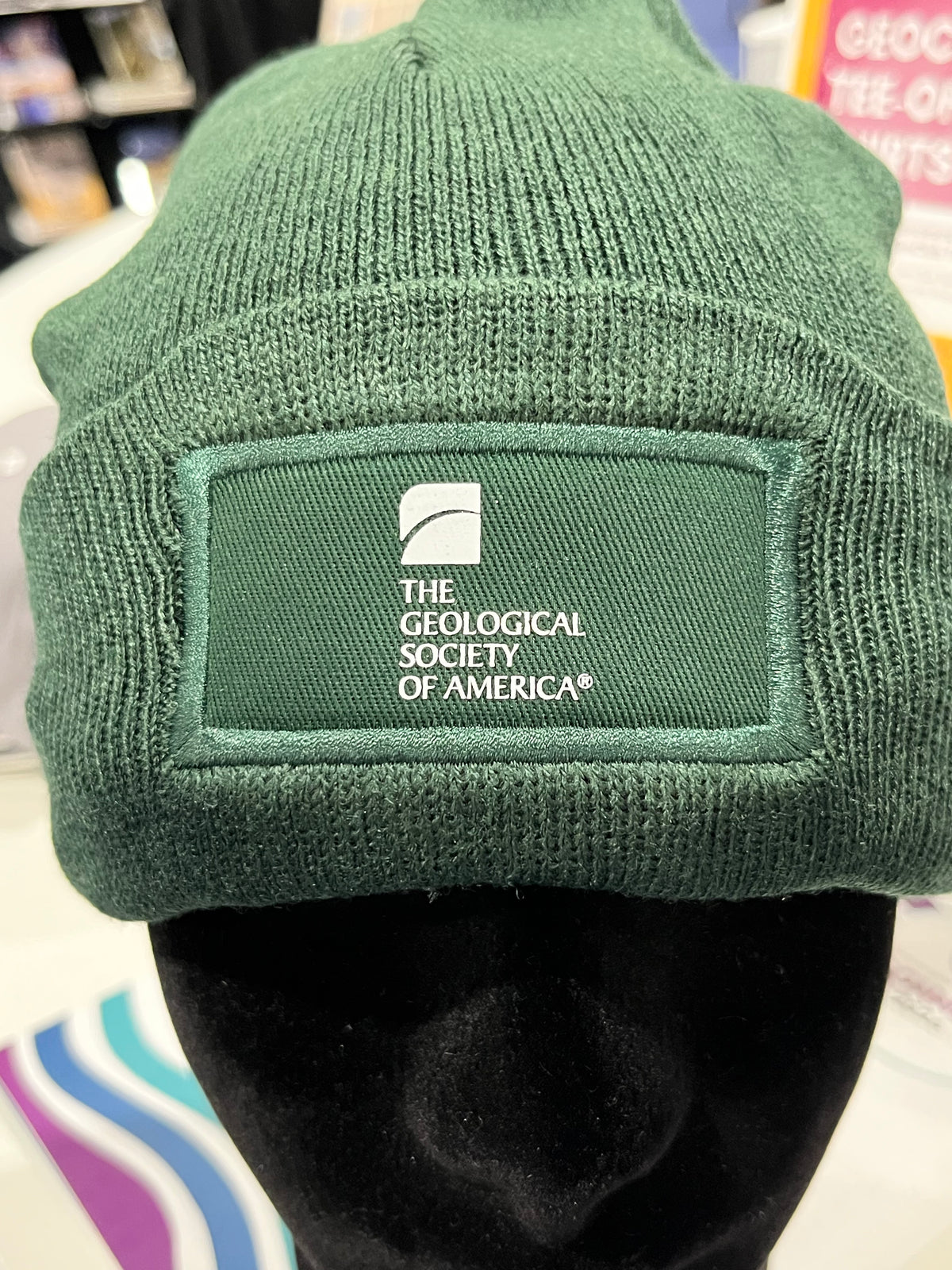 green beanie-style hat with a geological society of america logo 