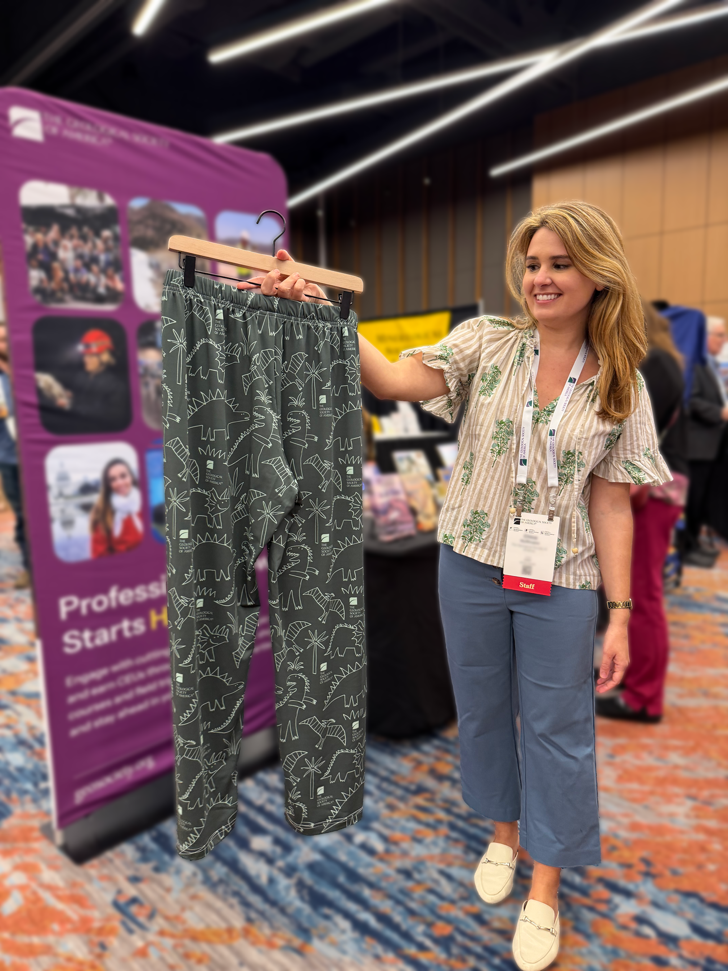 a woman holds a hanger with a pair of gsa pajama pants