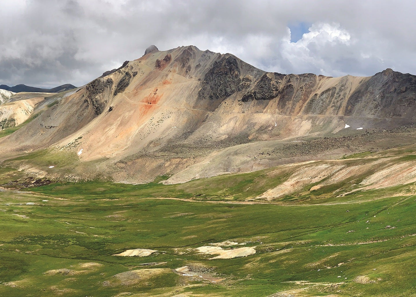 Panoramic view of a mountain landscape with green valleys and rocky peaks under a cloudy sky, Darley Mountain and Engineer Pass, Colorado 
