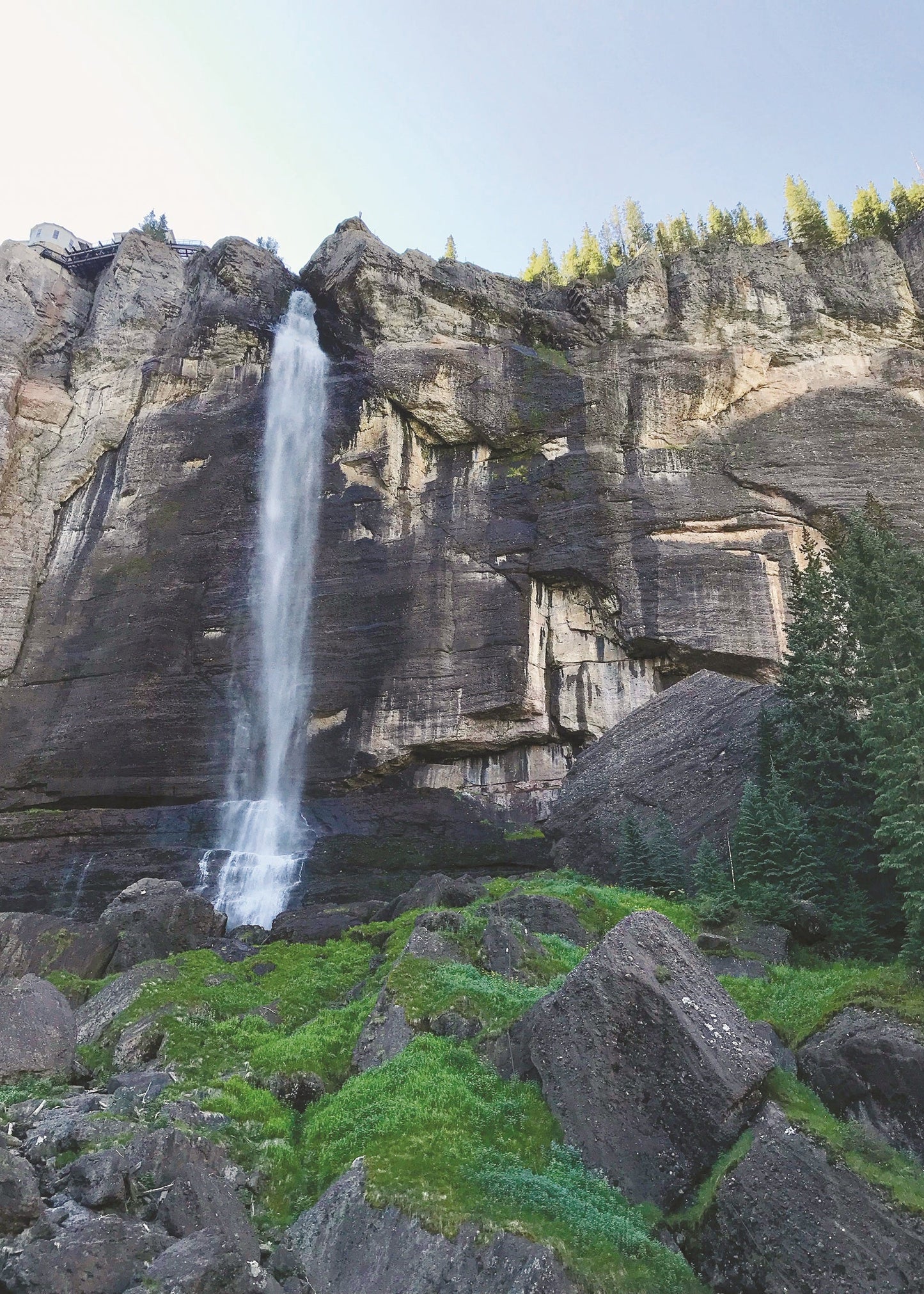 Waterfall cascading down a rocky cliff face with greenery, Telluride, Colorado 