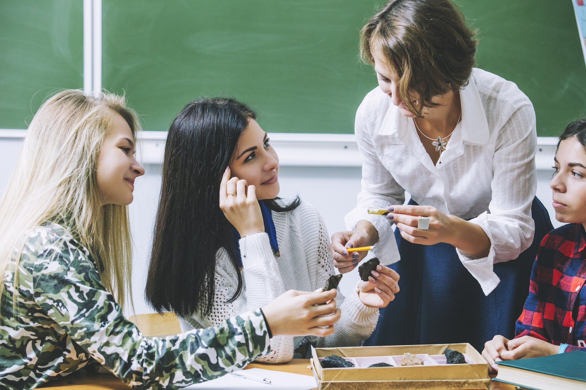 Four individuals examine rocks in a classroom setting. SC26SE01. Geoscience Learning image.