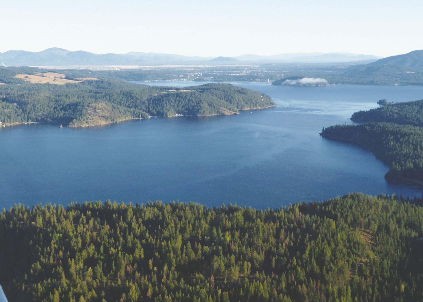 Aerial view of a large lake surrounded by forested areas and mountains, Idaho